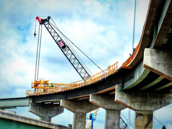 Beneath a bridge currently under construction with a large crane at the top.