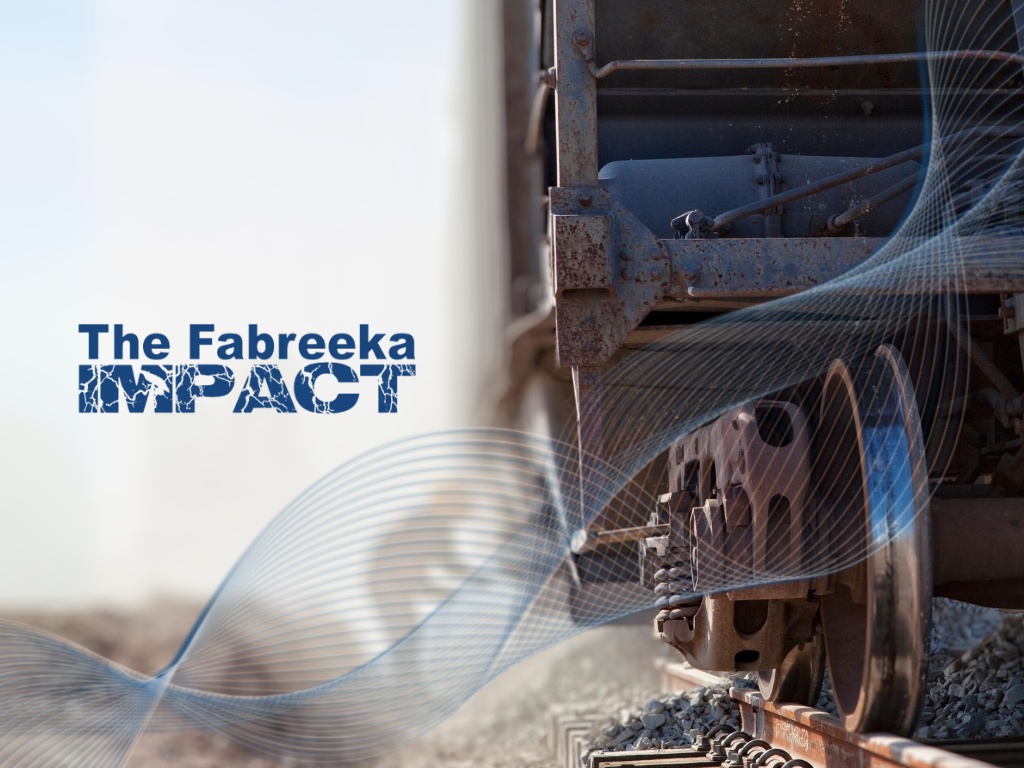 The Fabreeka Impact logo in front of a train car carrying railroad construction materials like Fabreeka Pad.